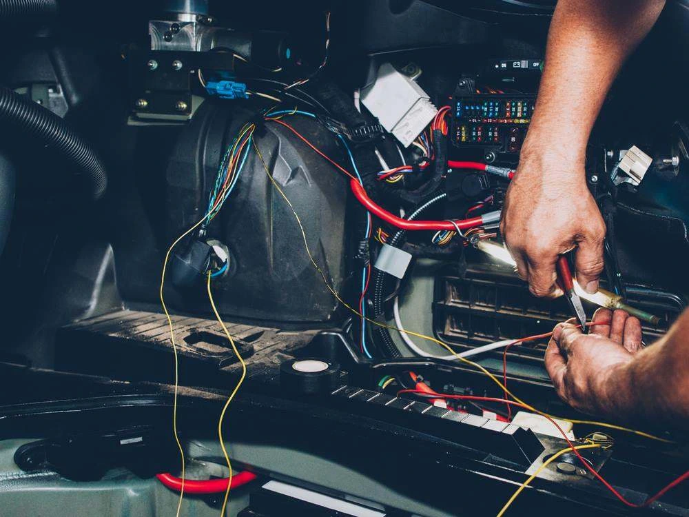 Auto electrical repair in progress on a vehicle's wiring harness and fuse box
