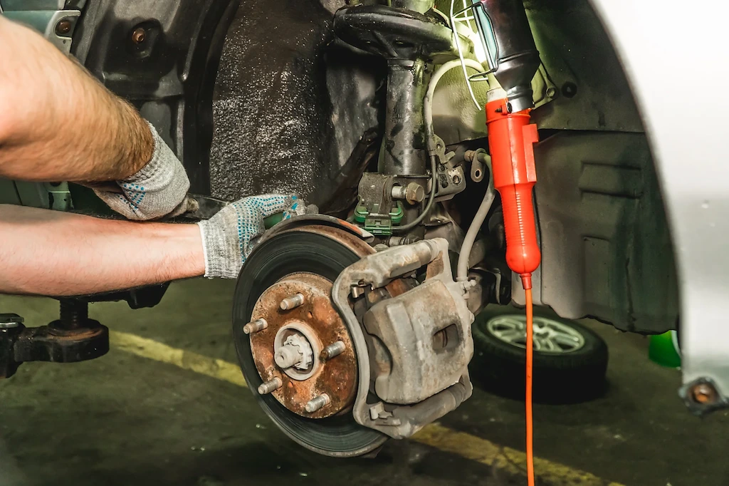Mechanic working on a front brake disc and caliper with the wheel removed