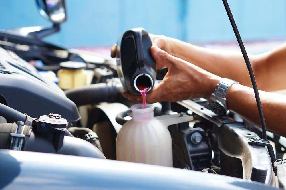 Coolant being topped up into a vehicle's overflow reservoir