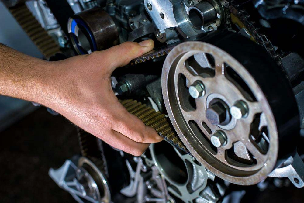 Mechanic checking a timing belt and camshaft pulley on an engine